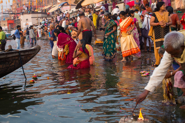 Varanasi, Indien - 22. März 2018: Am frühen Morgen stürzen sich Pilger in den Fluss Ganges. Der Legende nach wurde die Stadt vor etwa 5000 Jahren von Gott Shiva gegründet.. - Foto, Bild