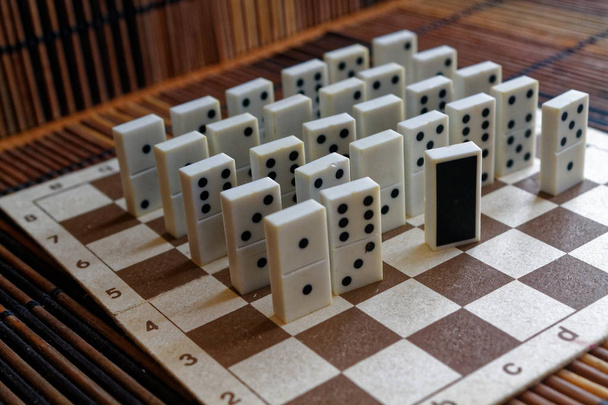 Domino stukken in een rij en een verschillende statnd, op de achtergrond van de bamboe bruin houten tafel - Foto, afbeelding