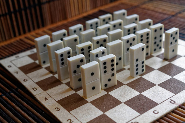 Domino stukken in een rij op de bamboe bruin houten tafel achtergrond - Foto, afbeelding
