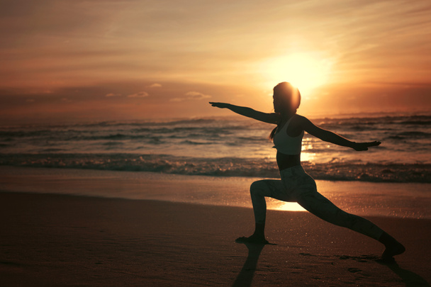 Joven deportista practicando yoga en la playa, concepto de vida sana y equilibrio natural entre desarrollo corporal y mental
 - Foto, Imagen