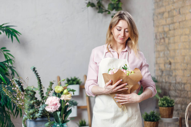 Photo of florist woman in apron with bouquet with kraft paper - Photo, image