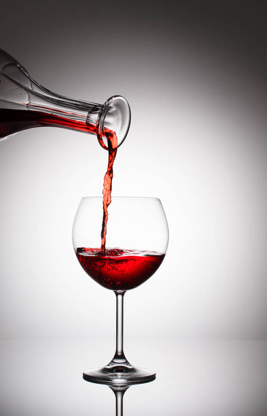 rode wijn wordt gegoten in een glas voor het serveren van verdere - Foto, afbeelding