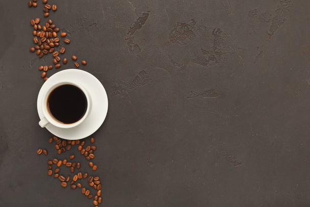 Cup of black coffee and scattered beans on gray background - Valokuva, kuva