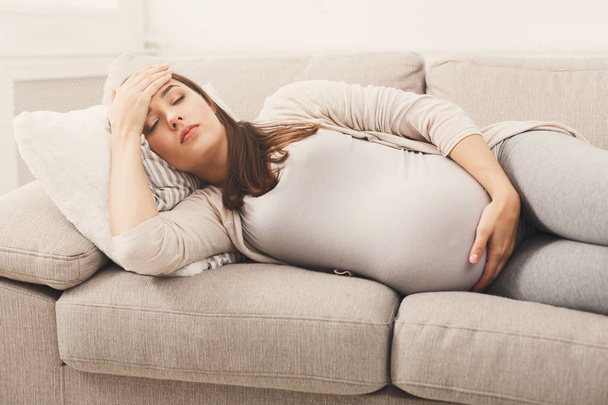 Young pregnant woman with headache lying on sofa - Zdjęcie, obraz