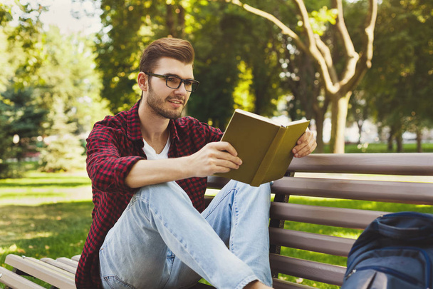 jonge man lezen van een boek buitenshuis - Foto, afbeelding