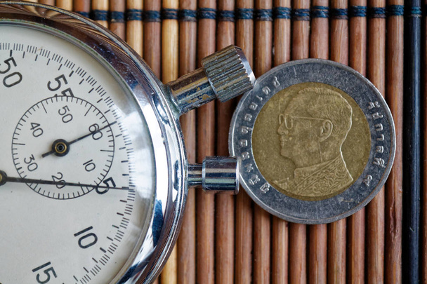 Moneda tailandesa con una denominación de cinco 10 y cronómetro en mesa de madera - reverso
 - Foto, imagen