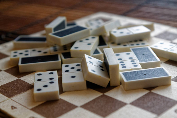 Chaotic pile of domino pieces on the bamboo brown wooden table background - Photo, Image