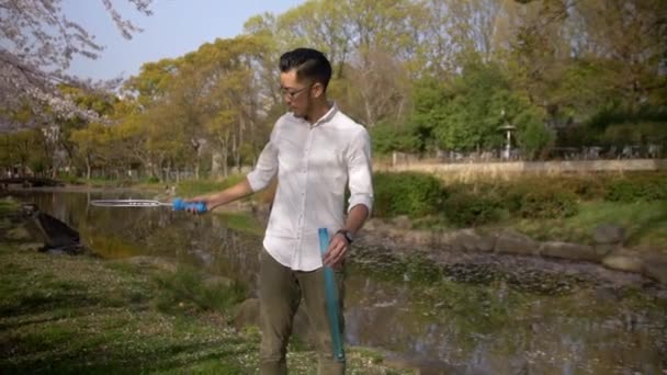 Handsom Asian man making bubbles by a beautiful pond in Japan. - Video