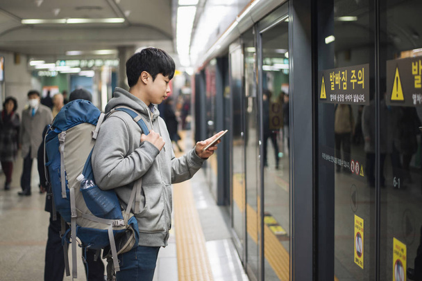Молода людина, подорожі в Кореї, чоловіки, чекаючи метро - Фото, зображення