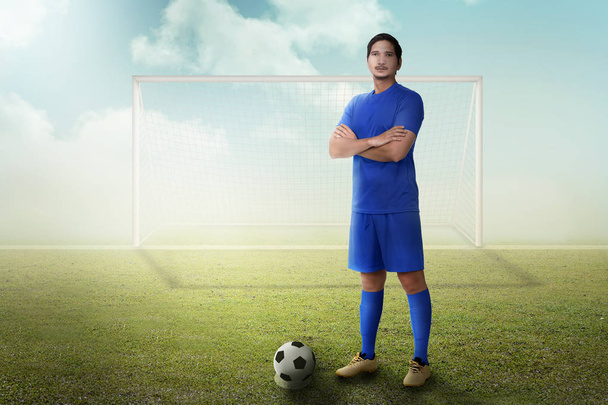 Handsome asian football player with arm crossed standing on the field - Photo, Image