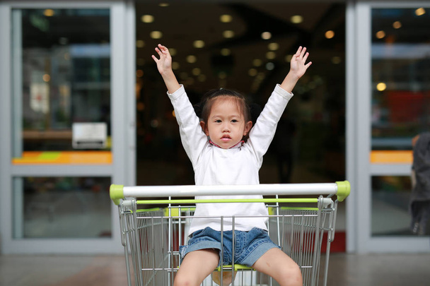 Asian little child girl sitting in the trolley during family shopping in the market. - Photo, image