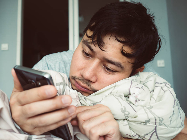 Man using his smartphone on his bed first thing after awake in t - Valokuva, kuva