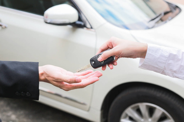 Salesman offering car key to a businessman from the car dealer. - Photo, Image