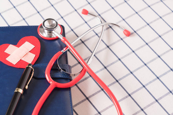 World health day healthcare and medical concept estetoscopio rojo y forma de corazón rojo en el cuaderno diario azul
 - Foto, imagen