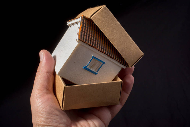Model huisje in hand in een doos papier - Foto, afbeelding