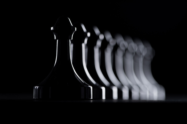 silhouettes of row of chess figures isolated on black, business concept - Photo, Image