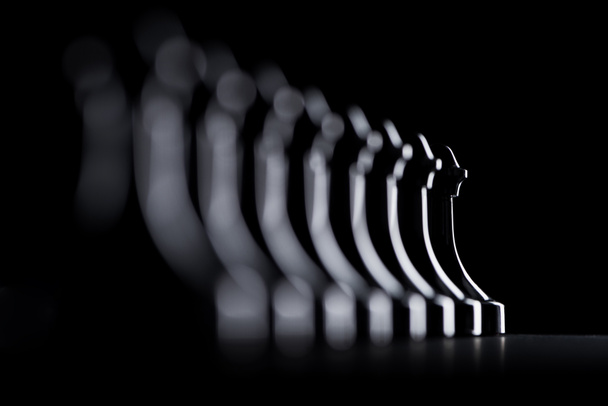 silhouettes de rangée de pions d'échecs isolés sur noir, concept d'affaires
 - Photo, image