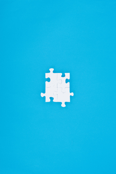 bovenaanzicht van geassembleerde wit puzzels geïsoleerd op blauw, bedrijfsconcept - Foto, afbeelding