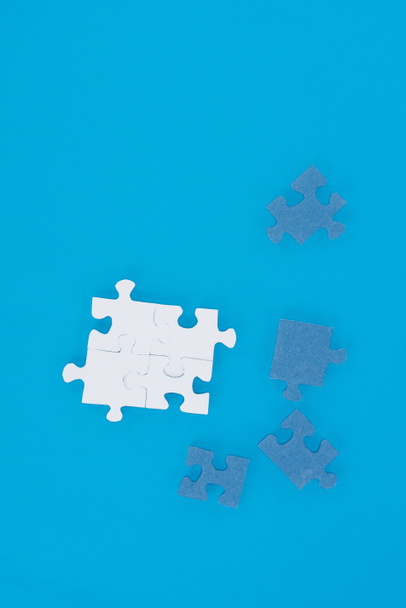 top view of white and blue puzzles isolated on blue, business concept - Photo, Image