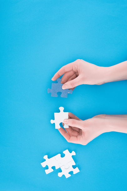 oříznutý obraz podnikatelka montáž modré a bílé puzzle izolované na modré, obchodní koncept - Fotografie, Obrázek