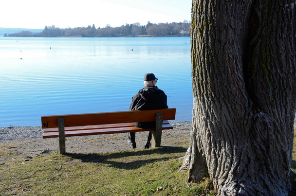 Чоловік на лавці біля озера
 - Фото, зображення