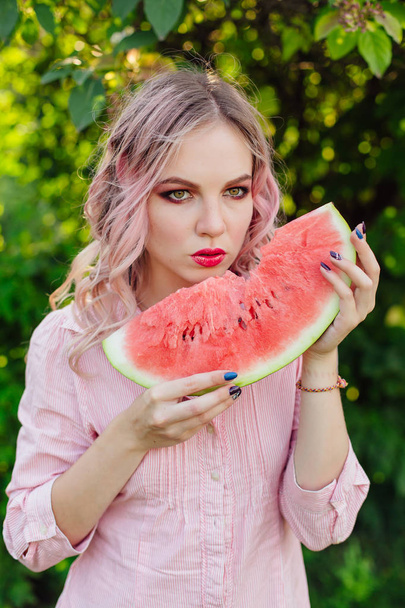 Beautiful young woman with pink hair enjoying watermelon - Foto, Imagen