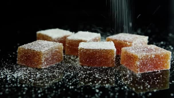 разбрызгивание сахаром оранжевой группы мармелада на фоне черного зеркала
 - Кадры, видео