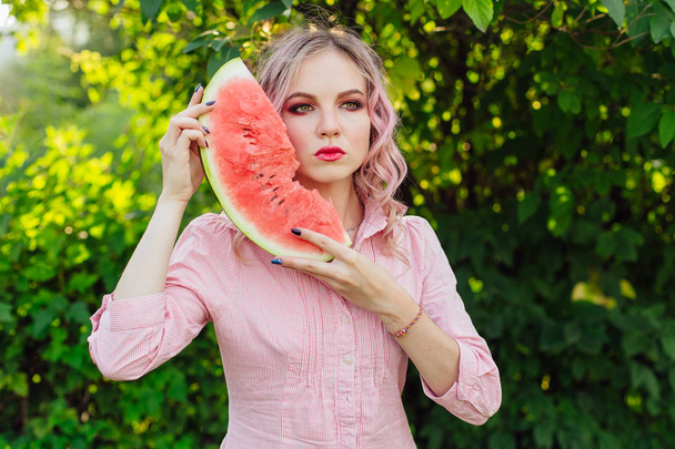 Beautiful young woman with pink hair enjoying watermelon - Фото, зображення