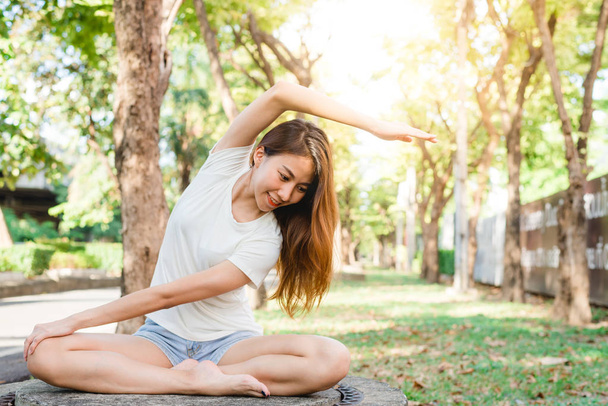 Jeune femme asiatique yoga en plein air garder le calme et médite tout en pratiquant le yoga pour explorer la paix intérieure. Yoga et méditation ont de bons avantages pour la santé. Yoga Sport et mode de vie sain concept
. - Photo, image