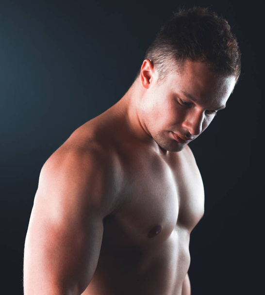 Healthy muscular young man. Isolated on black - Фото, изображение