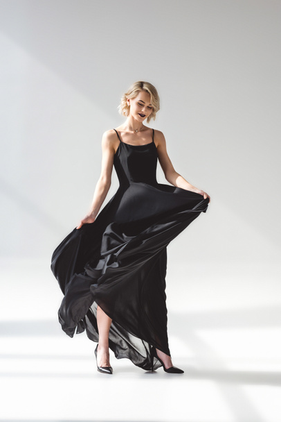 beautiful stylish girl posing in elegant black dress, on grey  - Foto, Bild
