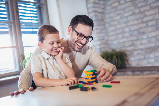 Father and adorable son playing with wooden blocks at table - Photo, Image