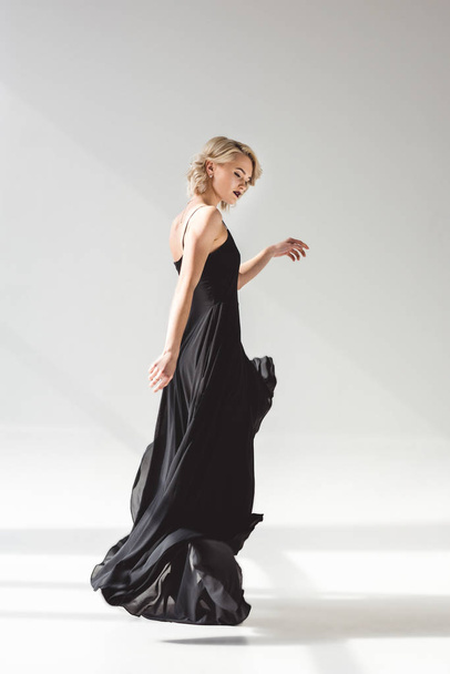 stylish girl posing in elegant black dress for fashion shoot, on grey  - 写真・画像