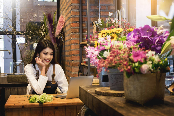 Women florist looking laptop got order at counter of her flower  - Photo, Image