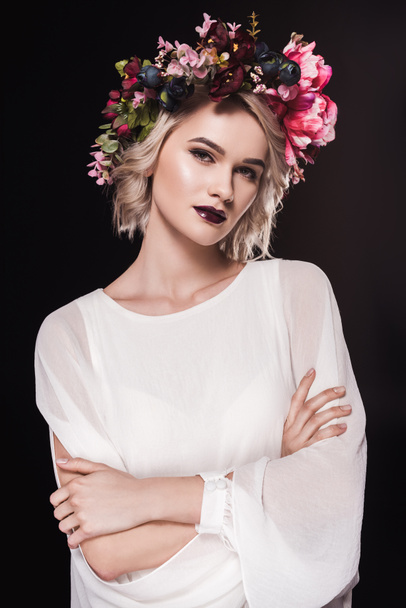 attractive blonde girl posing in white dress and floral wreath, isolated on black - Photo, Image