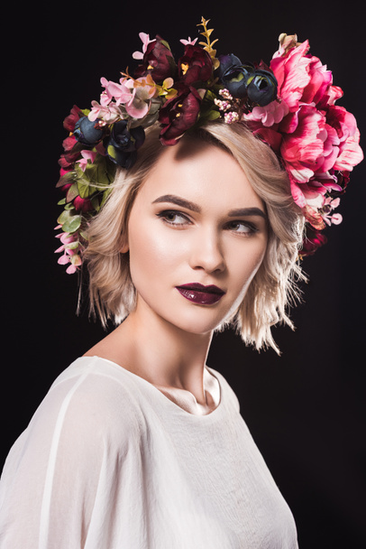 portrait of beautiful blonde girl posing in floral wreath, isolated on black - Фото, изображение