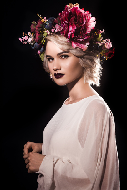 fashionable girl posing in white dress and floral wreath, isolated on black - Fotó, kép