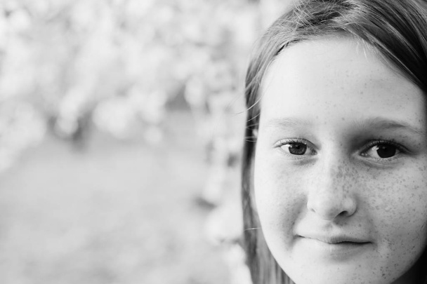 Closeup portret van tiener meisje lopen op landelijke bloesem park overdag - Foto, afbeelding
