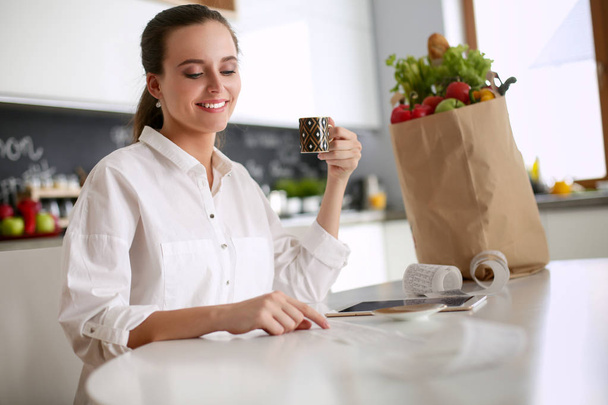 Young woman planning expenses and paying bills on her kitchen. - Photo, Image