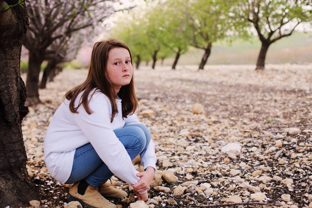 Nahaufnahme Porträt eines Teenie-Mädchens, das tagsüber auf dem ländlichen Blütenpark spaziert - Foto, Bild