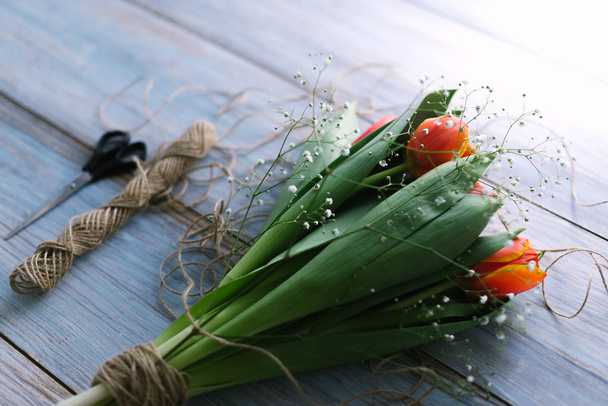 Blossoming tulips with a rope on a wooden light background - Valokuva, kuva