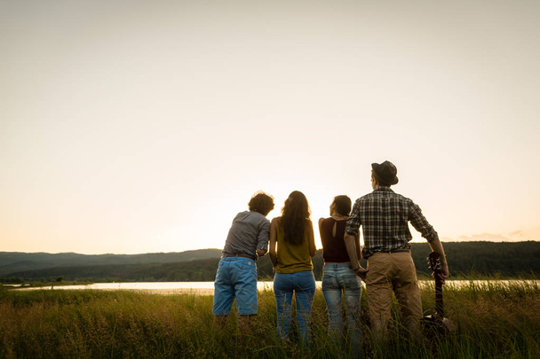 Grupo de amigos en el atardecer del día de verano mirando al horizonte
 - Foto, imagen