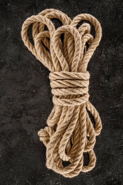 top view of tied brown nautical rope on dark concrete tabletop - Foto, Bild