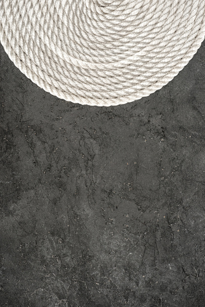 top view of white nautical rope arranged in circle on dark concrete tabletop - Foto, Bild