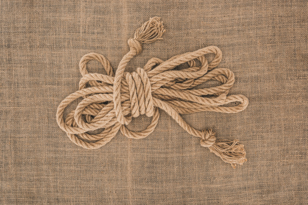 top view of arranged tied brown nautical rope on sackcloth - Φωτογραφία, εικόνα