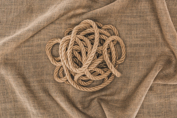 vista superior de cuerda náutica marrón arreglada sobre tela de saco
 - Foto, imagen