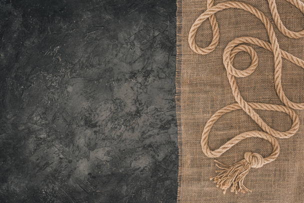 top view of arranged brown nautical rope on sackcloth on dark concrete tabletop - Photo, Image