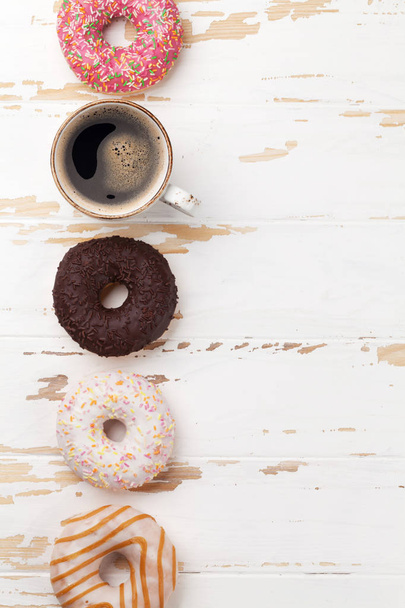 Coffee cup and donuts on white wooden table. Top view with space - Foto, afbeelding