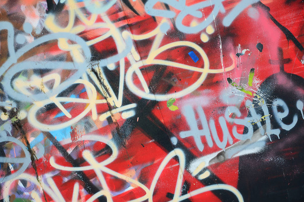 Fragmento de primer plano de un dibujo de graffiti aplicado a la pared por pintura en aerosol. El muro está estropeado por una multitud de coloridas firmas y etiquetas de artistas callejeros y vándalos
 - Foto, Imagen