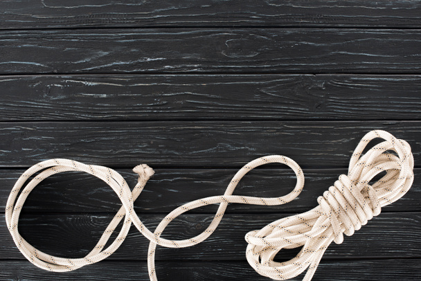 top view of tied white marine rope on dark wooden tabletop - Foto, afbeelding